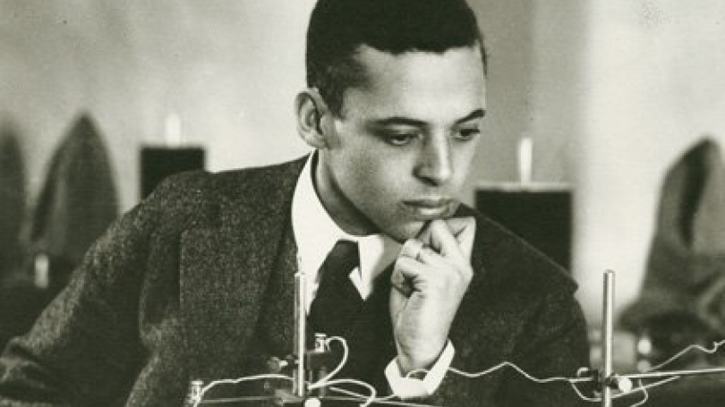 Dr. Ernest Everett Just at a laboratory table, resting his chin on his hand