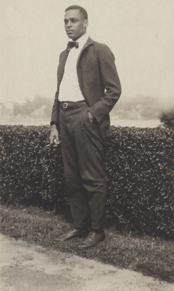 Dr. Ernest Everett Just standing outdoors beside a hedge